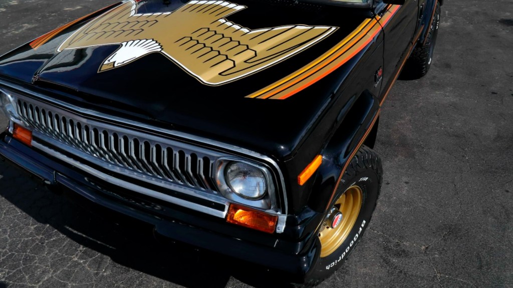 The eagle hood graphic on a black-and-gold 1978 Jeep J10 Golden Eagle in a parking lot