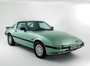 A seafoam green 1991 Mazda RX-7 on a white background and floor. 