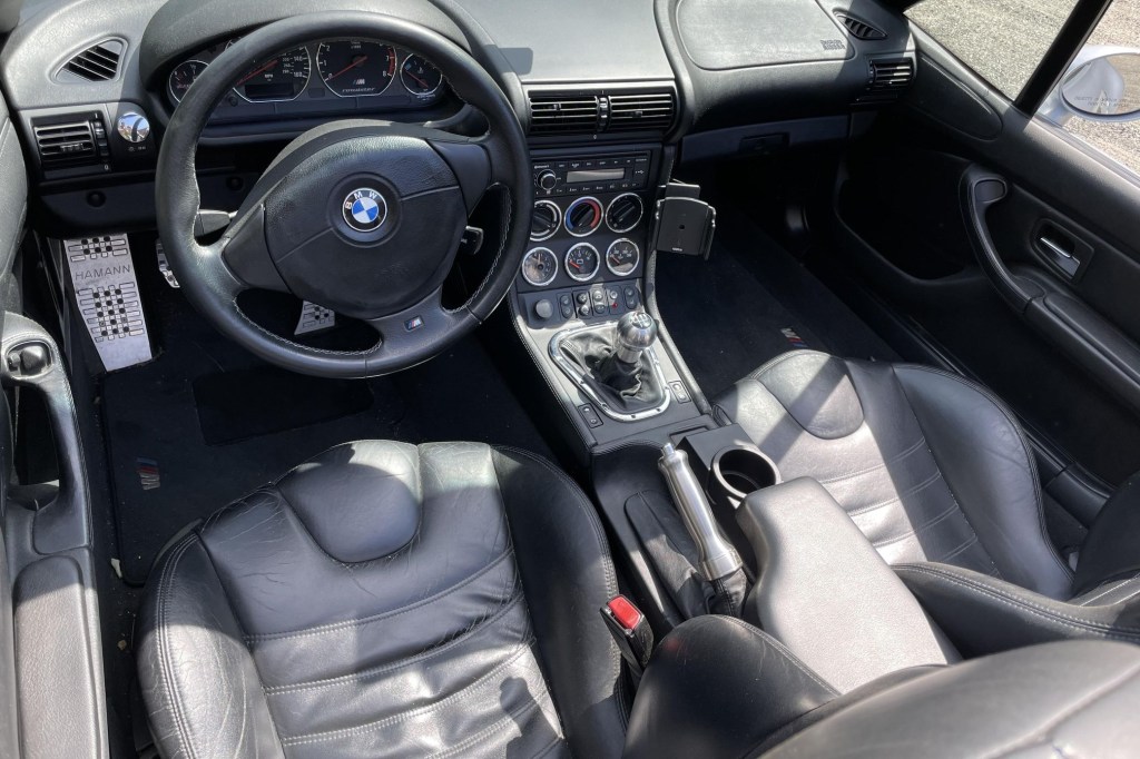 The black-leather-upholstered interior of a 1998 BMW Z3 M Roadster with some aftermarket accessories
