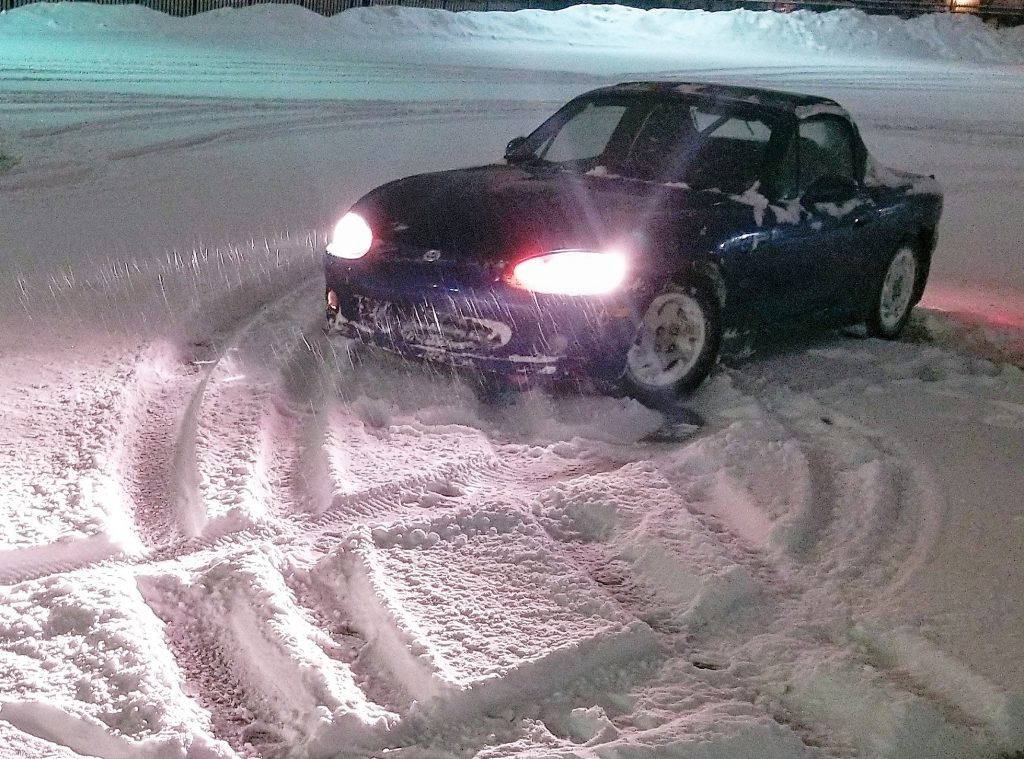 A Mazda Miata driving in the snow 
