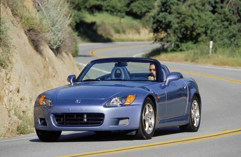 A gray 2003 'AP1' Honda S2000 driving around a curving mountain road