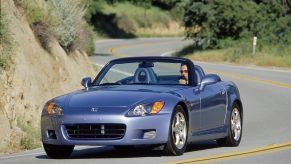 A gray 2003 'AP1' Honda S2000 driving around a curving mountain road