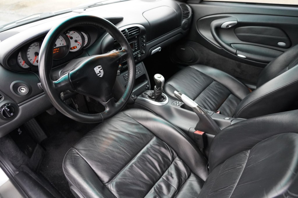 The black-leather-upholstered front seats and dashboard of a 2003 Porsche 911 Carrera 4S