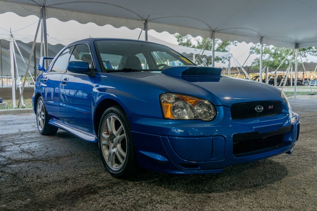 A blue 2004 Subaru Impreza WRX STi under a tent at the 2021 Chicago Mecum auction