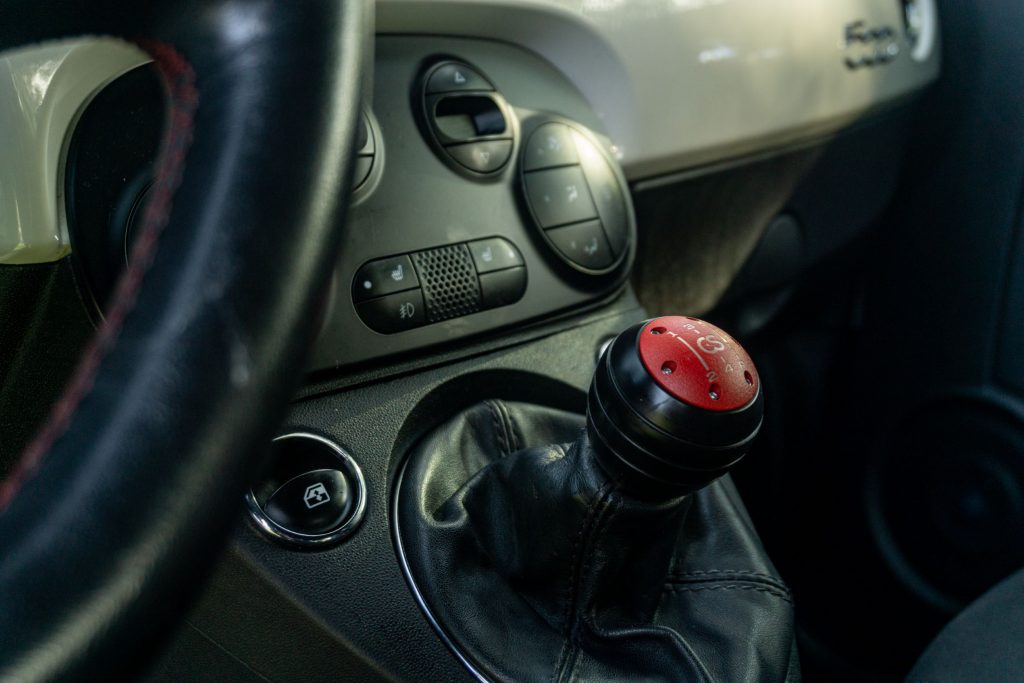 A red-and-black CravenSpeed short shifter in a 2013 Fiat 500 Abarth