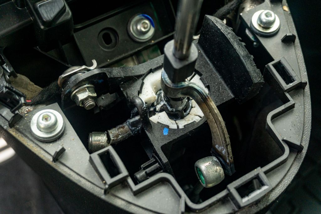 A close-up view of the retaining clip and shift cable connectors attached to a 2013 Fiat 500 Abarth's stock shifter assembly