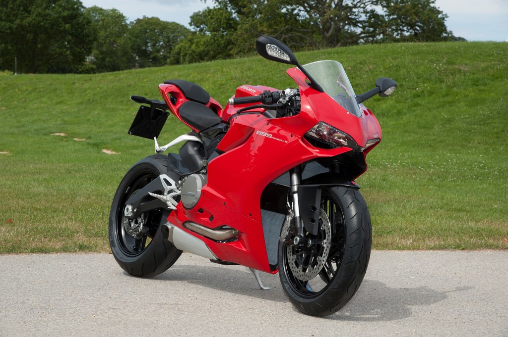 A red 2014 Ducati 899 Panigale motorcycle next to a grassy field