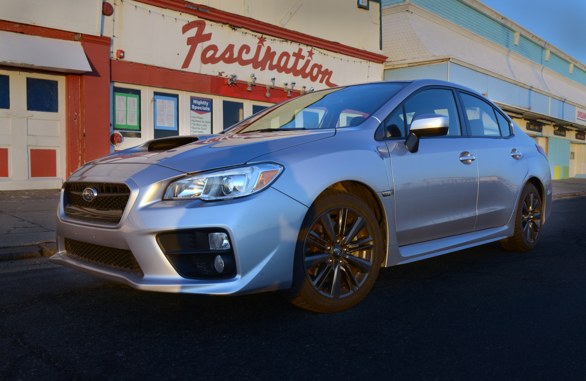 A silver WRX shot from the front 3/4 angle in a parking lot at sunset