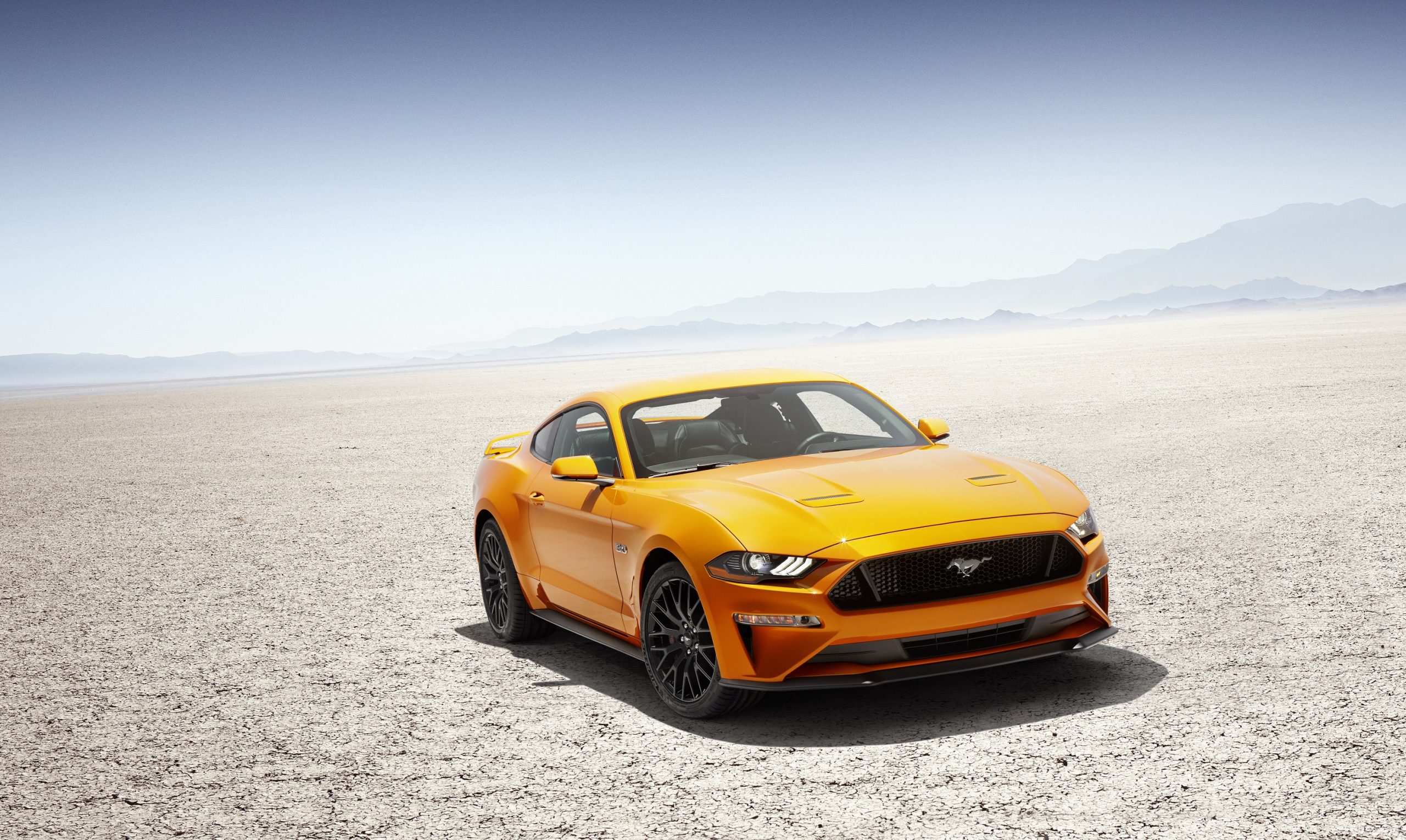 An orange Ford Mustang shot from the front 3/4 in the desert
