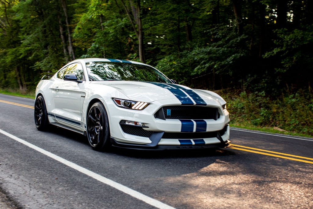 A white-with-blue-stripes 2020 Ford Mustang Shelby GT350R Heritage Edition on a forest mountain road