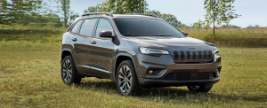 The 2021 Jeep Cherokee 80th Anniversary Edition compact SUV parked in a grass field