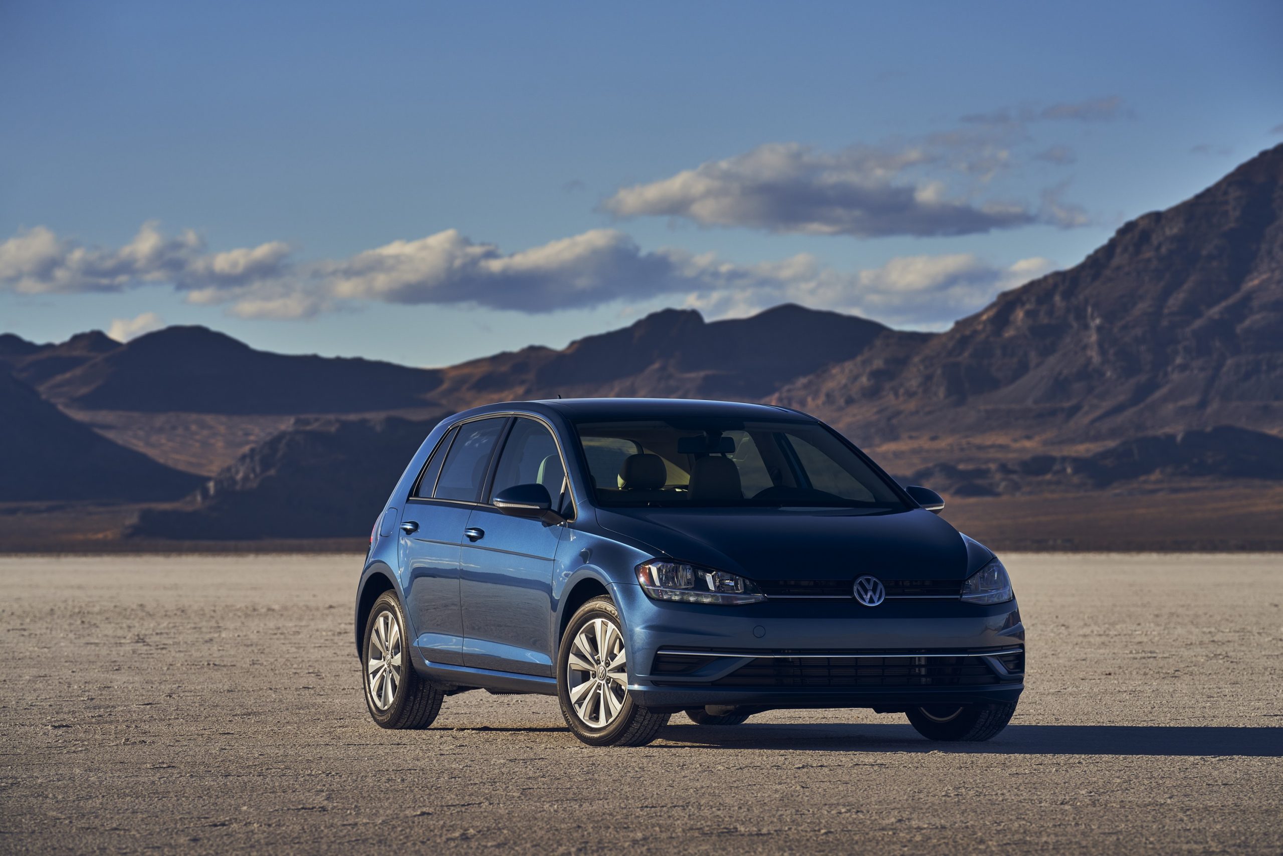 A dark turquoise blue 2021 Volkswagen Golf hatchback shot from the front 3/4 on a lake bed