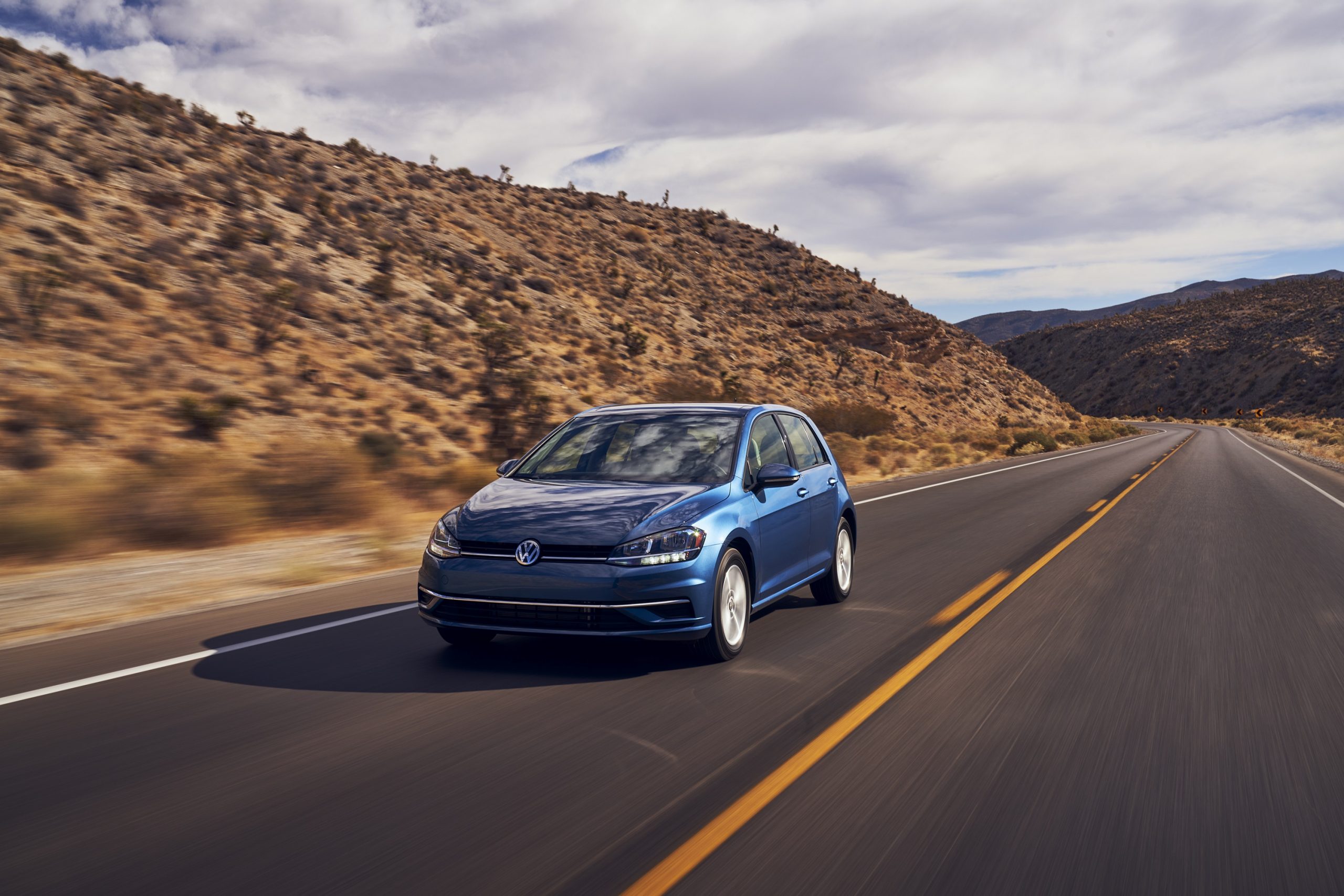 A blue 2021 Volkswagen Golf hatchback shot from the front 3/4 on a canyon road
