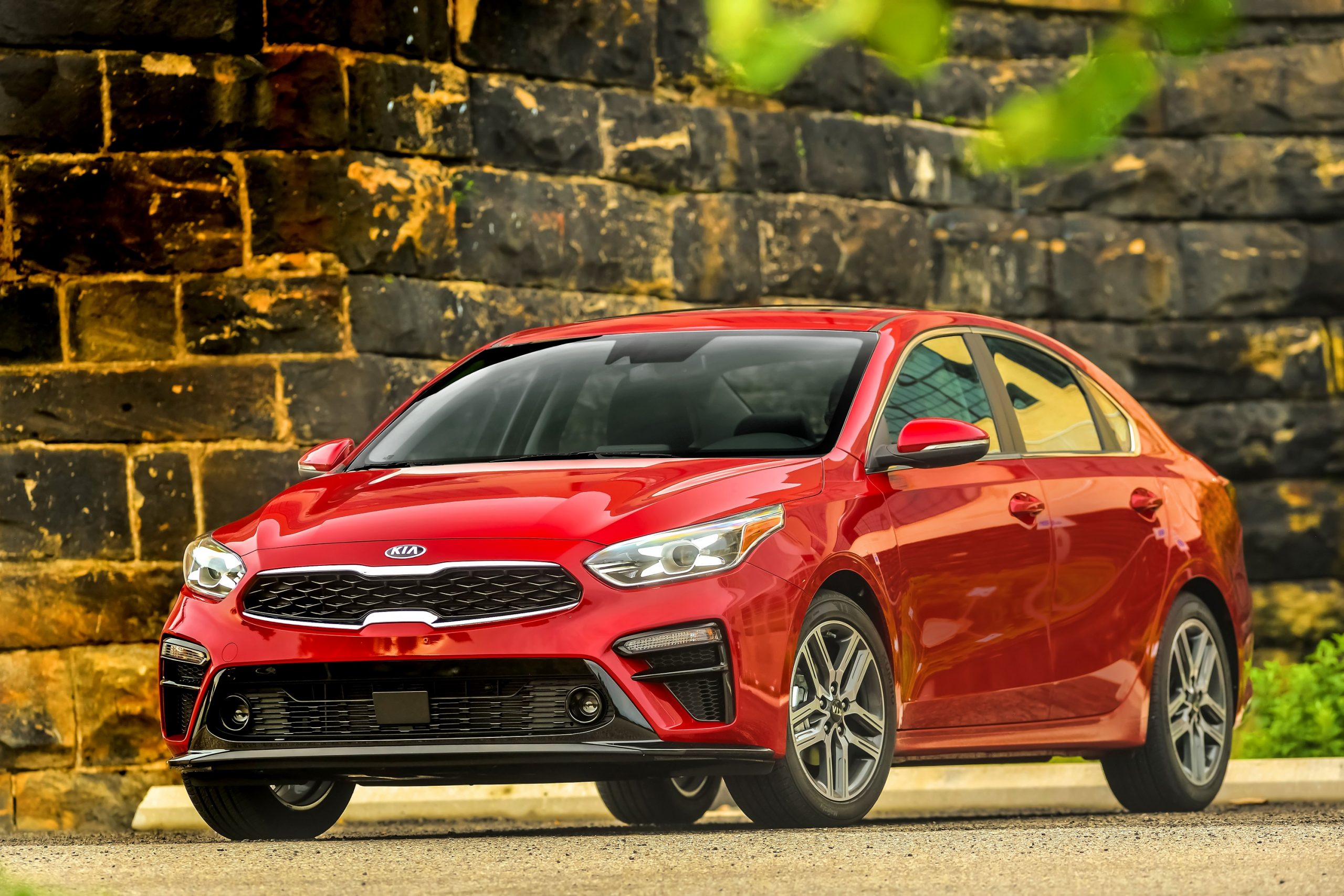 A red 2021 Kia Forte shot from the front 3/4 on a gravel road