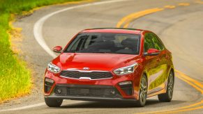 A red 2021 Kia Forte compact sedan shot from the 3/4 angle on a back road