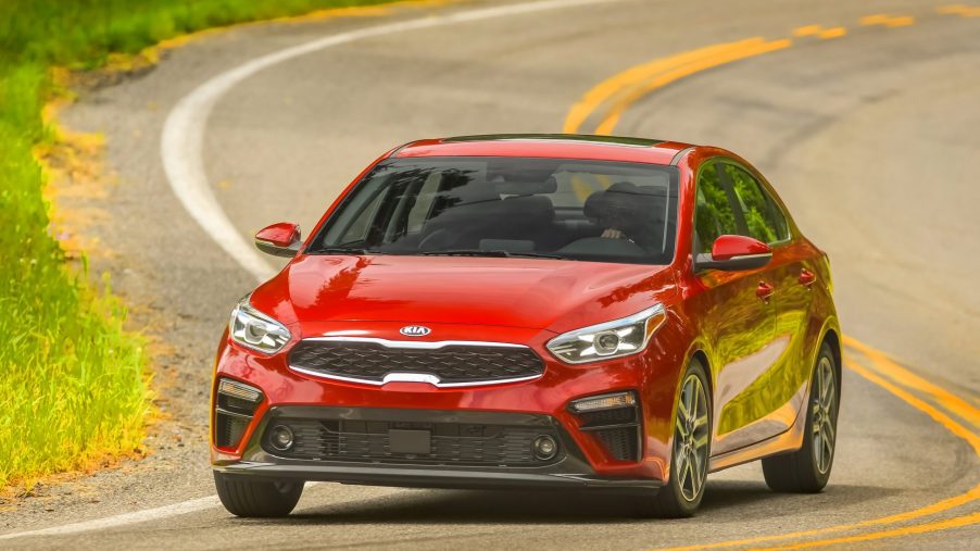 A red 2021 Kia Forte compact sedan shot from the 3/4 angle on a back road