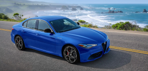 The 2022 Alfa Romeo Giulia luxury midsize sedan with a blue paint color option parked on a highway near the ocean of crashing waves