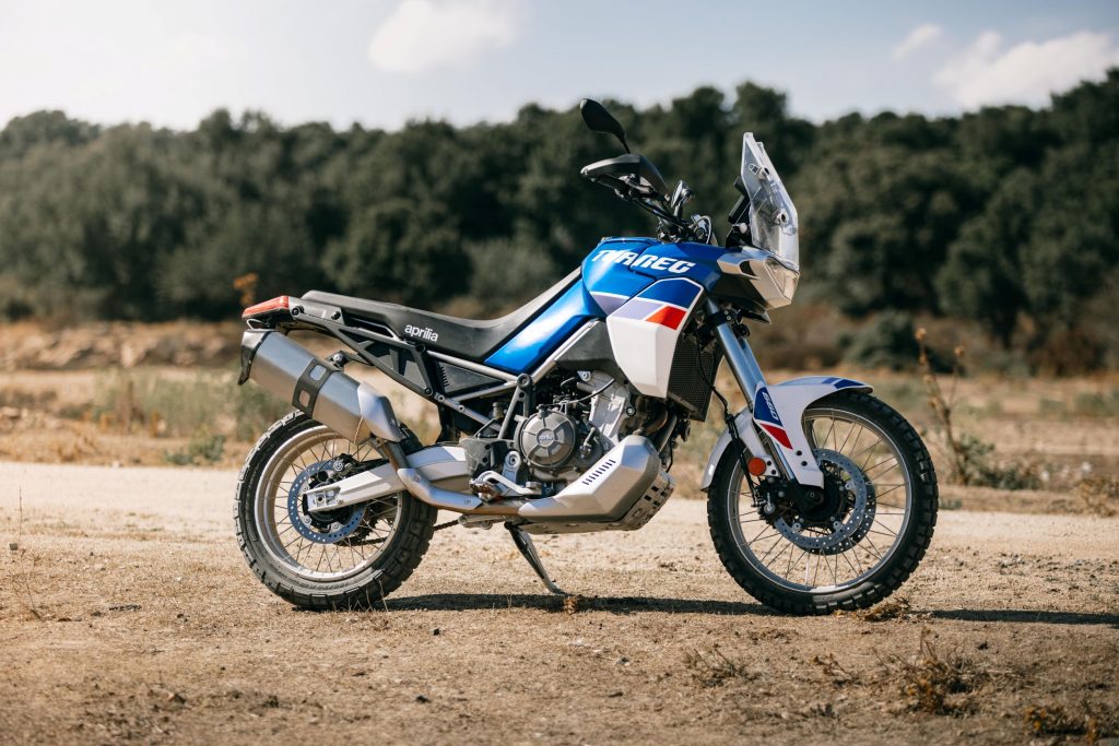 The side view of a blue-white-and-red 2022 Aprilia Tuareg 660 Indaco Tagelmust in the desert