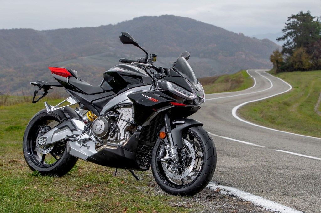 A black 2022 Aprilia Tuono 660 Factory Edition parked by a winding country road