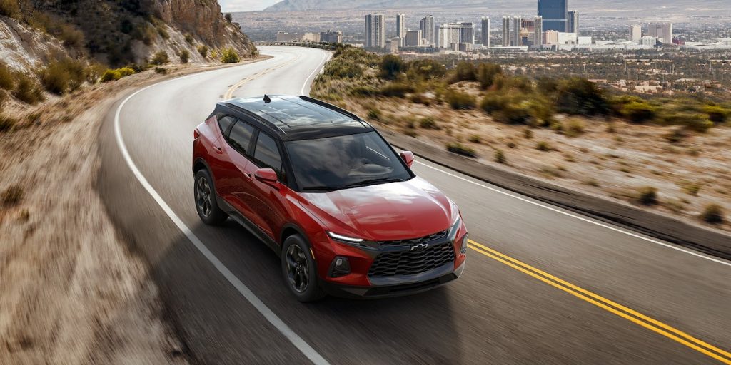 A red 2022 Chevy Blazer driving on a road with a city in the background, what's new for 2022?