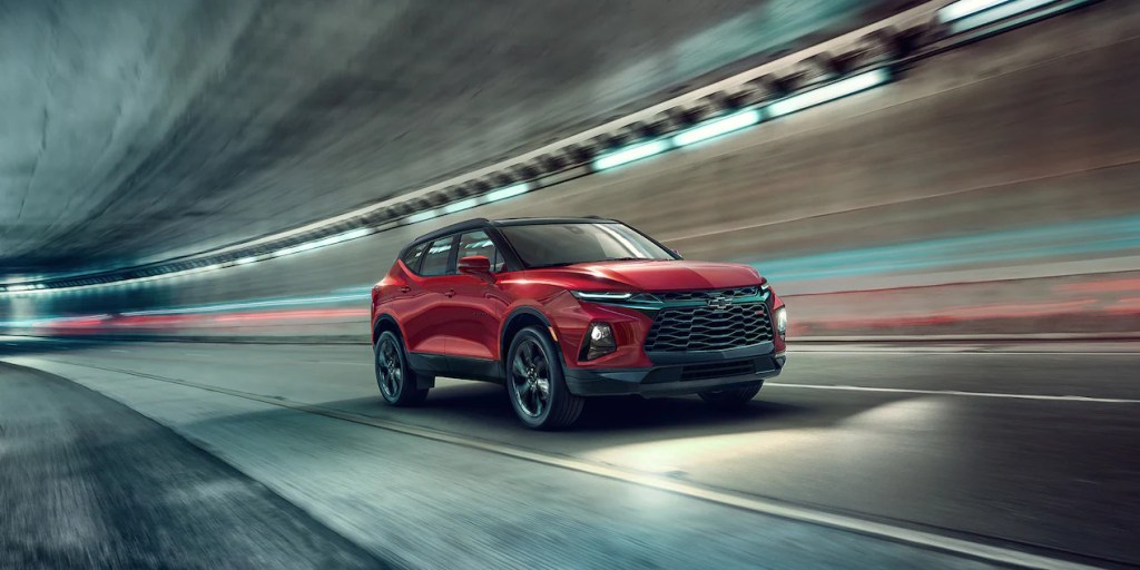 A red 2022 Chevy Blazer midsize crossover SUV drives through a tunnel at night