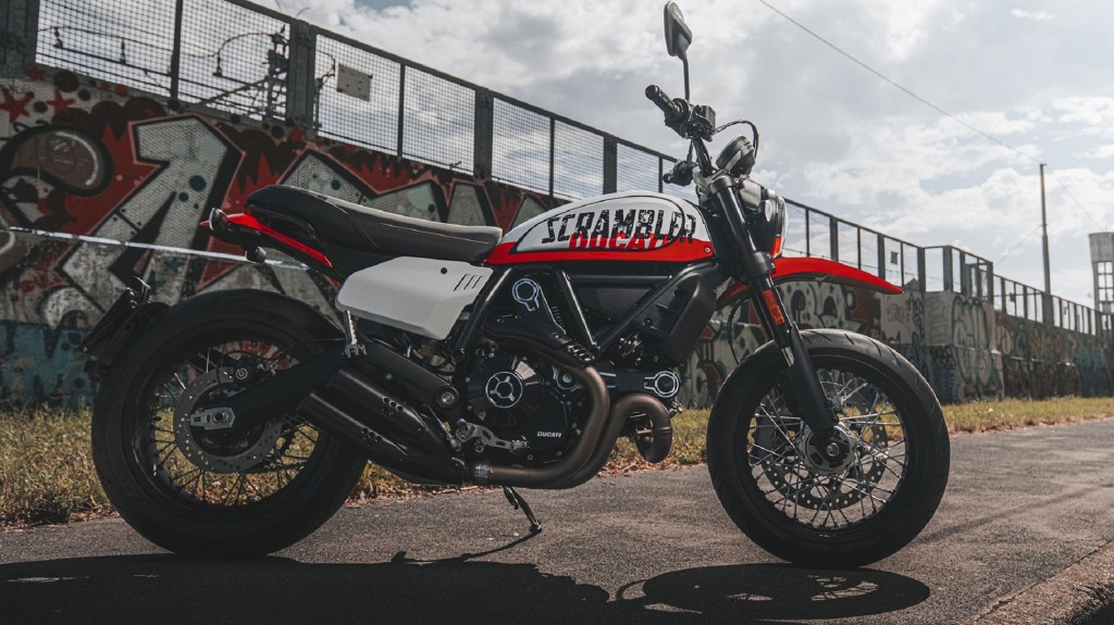 The side view of the white-and-red 2022 Ducati Scrambler Urban Motard on a city street