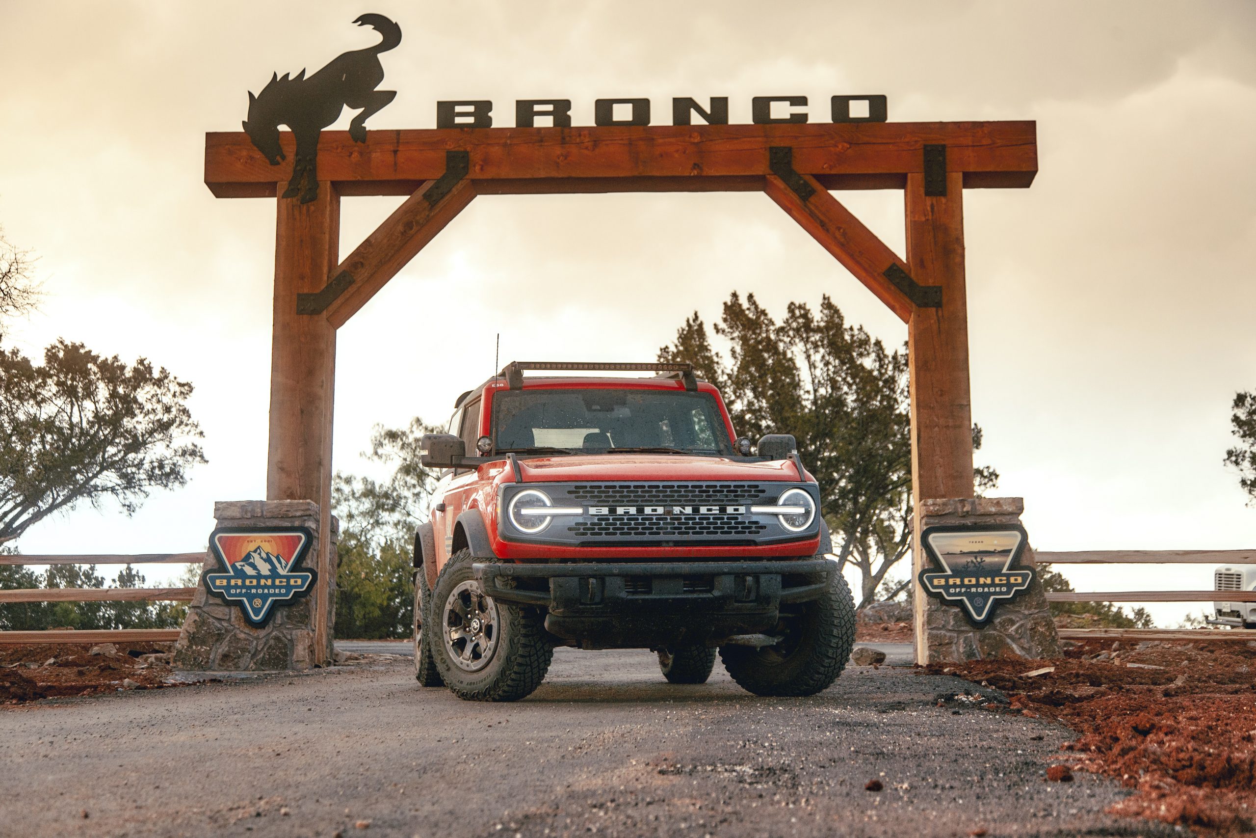 A red 2022 Ford Bronco parked near a large wooden Bronco sign, is the Wildtrak trim worth the price tag?