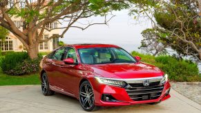 A red 2022 Honda Accord midsize sedan shot from the front 3/4 in an orchard