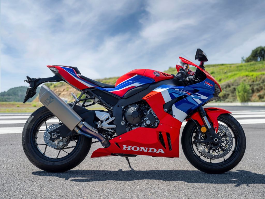 The side view of a red-blue-and-white 2022 Honda CBR1000RR-R Fireblade on a racetrack