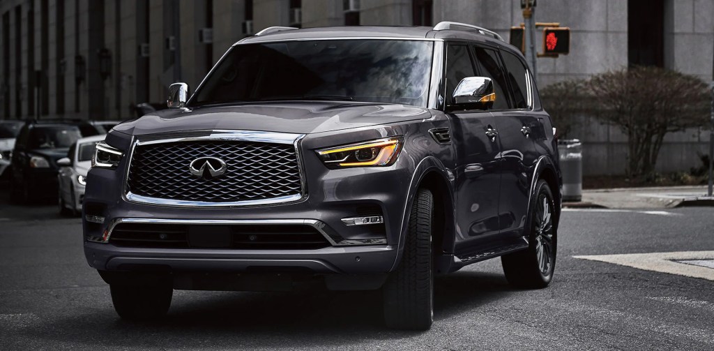 A Gray 2022 Infiniti QX80 turning through an intersection in the city, the largest of the Infiniti SUV models.