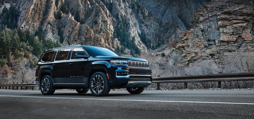A black 2022 Jeep Grand Wagoneer drives alongside a mountain background, it is being recalled.
