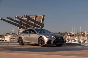 The 2022 Lexus LS 500 F-Sport full-size luxury sedan with a Atomic Silver paint color option parked near a sea dock filled with boats