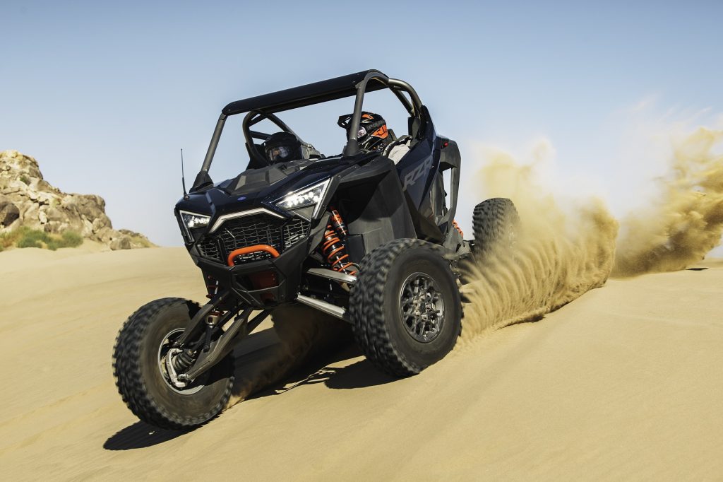 The front 3/4 view of a black 2022 Polaris RZR Pro R Ultimate going down a dune