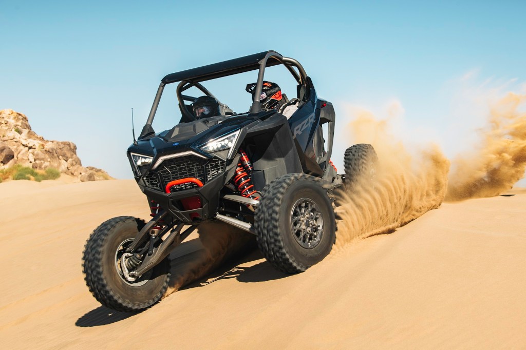 The front 3/4 view of a black 2022 Polaris RZR Pro R Ultimate going down a dune