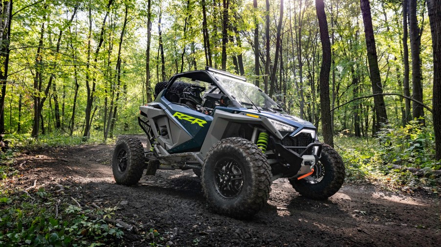 A green-and-gray 2022 Polaris RZR Turbo R Premium in the forest