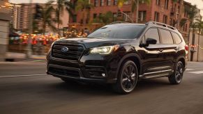 The 2022 Subaru Ascent Onyx Edition three-row midsize SUV with the Crystal Black Pearl paint color option driving through a city