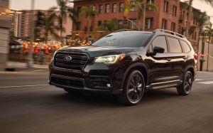 The 2022 Subaru Ascent Onyx Edition three-row midsize SUV with the Crystal Black Pearl paint color option driving through a city