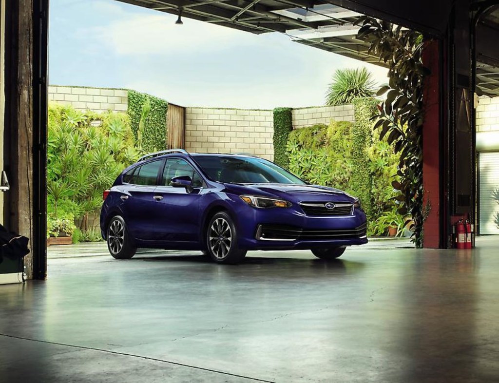 The 2022 Subaru Impreza compact sedan with a dark blue color option parked at the entrance of an option garage