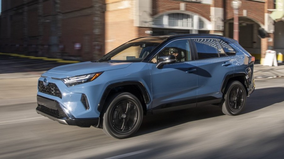 2022 Toyota RAV4 with Cavalry Blue color option driving by a brick building