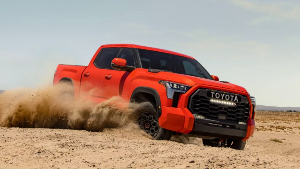 An orange Toyota Tundra off-road pickup truck drives through the dirt.