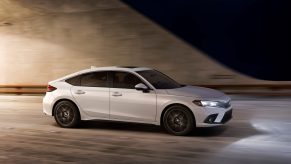A white 2022 Honda Civic hatchback shot in profile on a highway at night