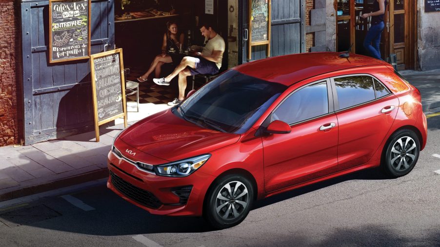 A red 2022 Kia Rio hatchback shot from the high 3/4 on a city side street