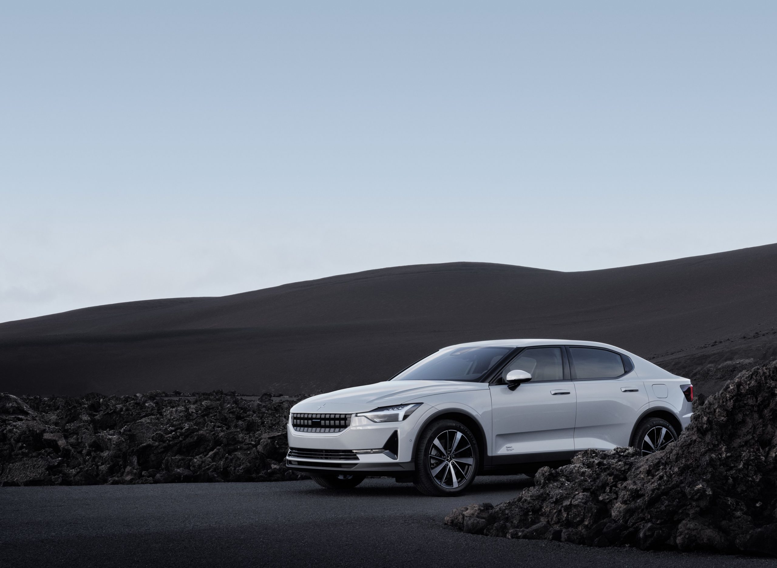 A white 2022 Polestar 2 luxury sedan shot from the front 3/4 in a volcanic boulder field