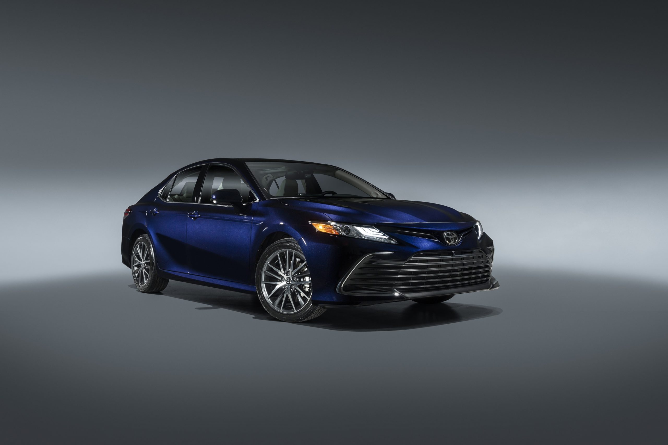 A dark blue Toyota Camry shot from the front 3/4 in a photo studio