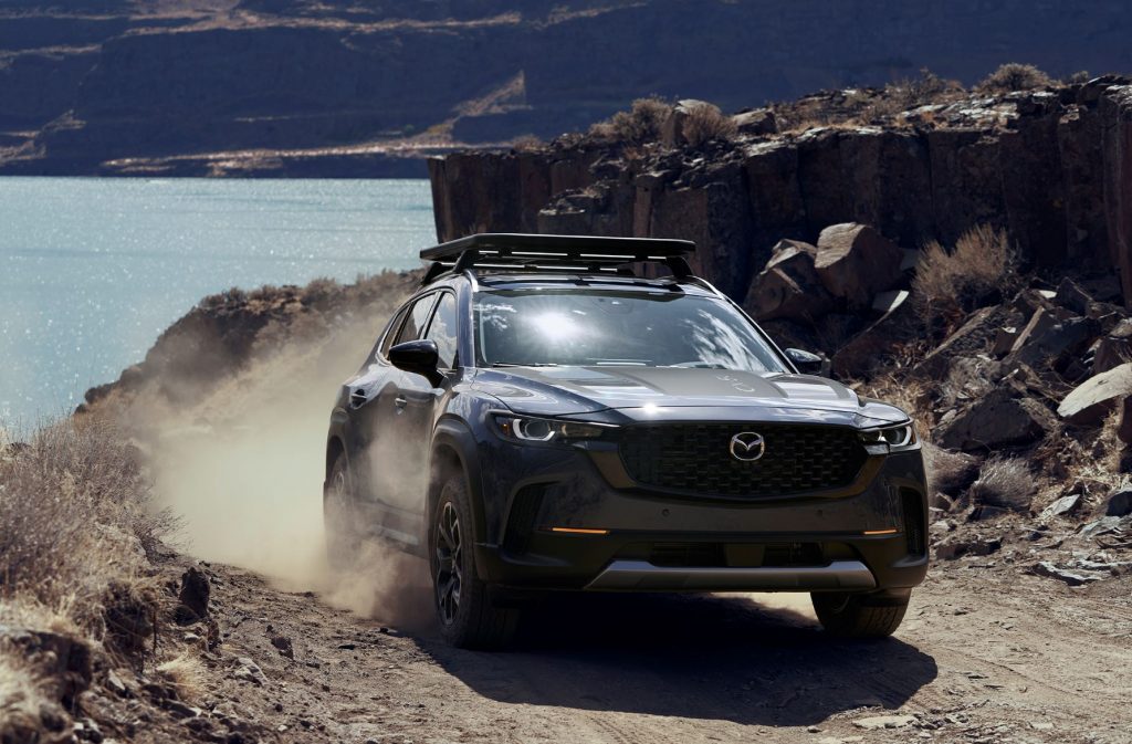 2023 Mazda CX-50 driving on a rocky road near a lake