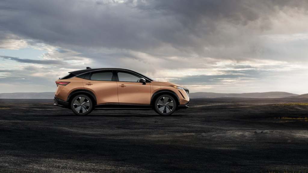 A peach 2023 Nissan Ariya electric crossover parked with a dark and stormy background
