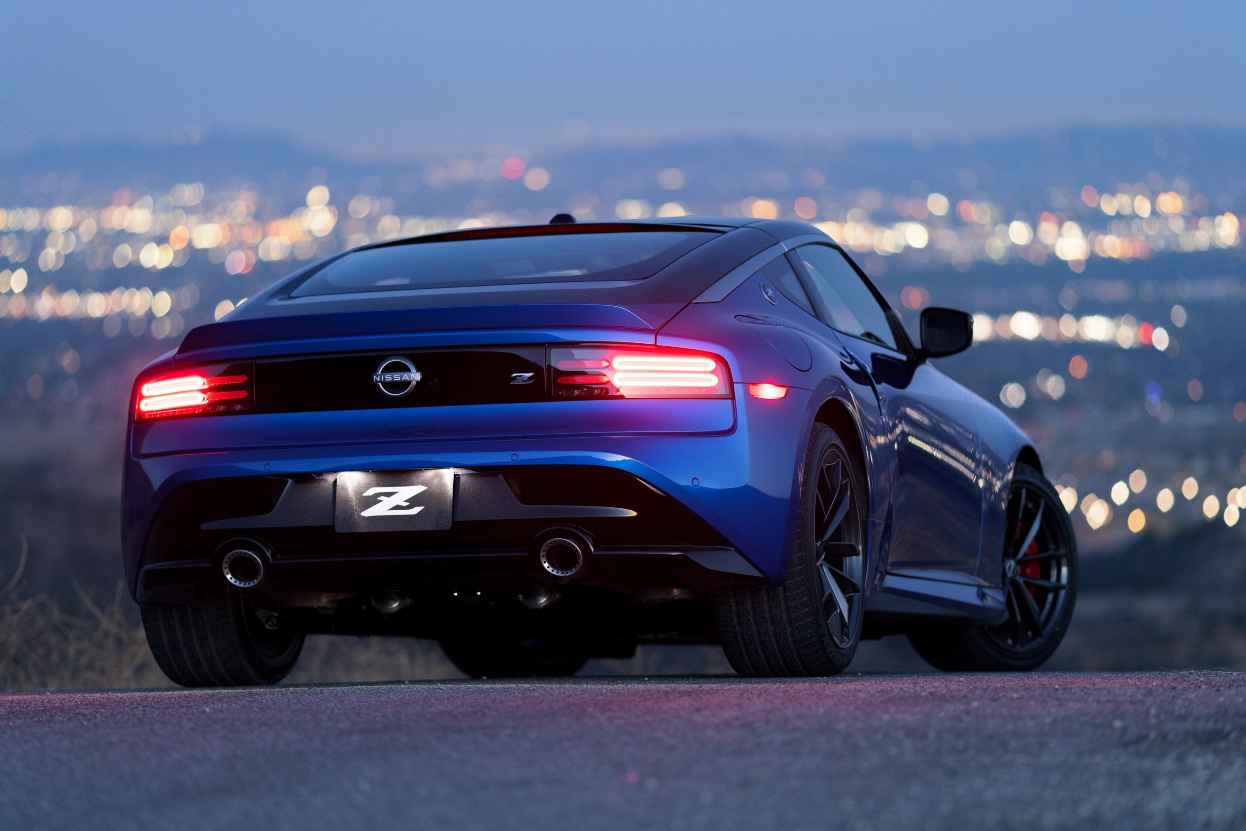A low rear 3/4 shot of a dark blue Nissan Z at night