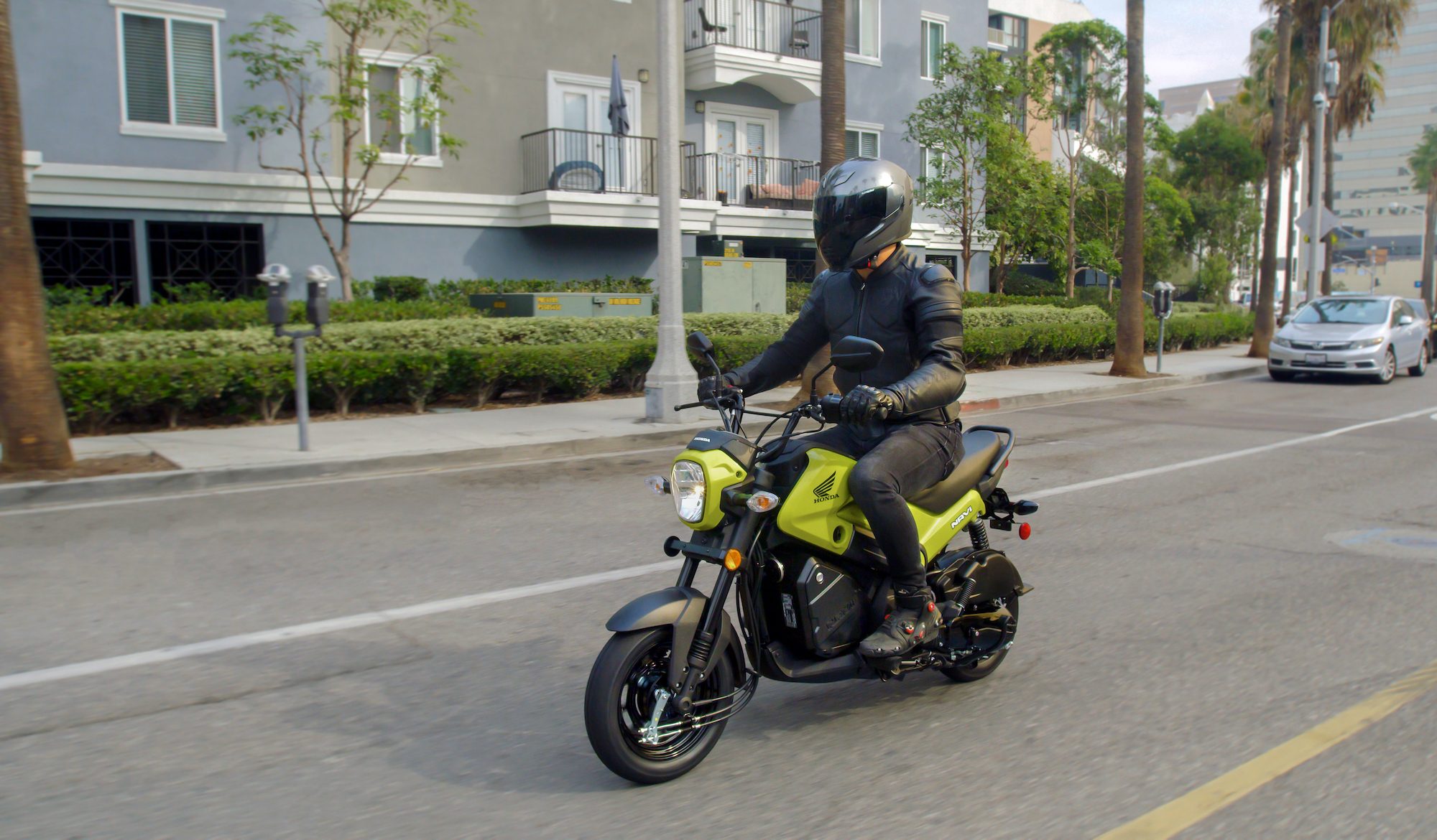 A rider rides a 2022 Honda Navi through a city street