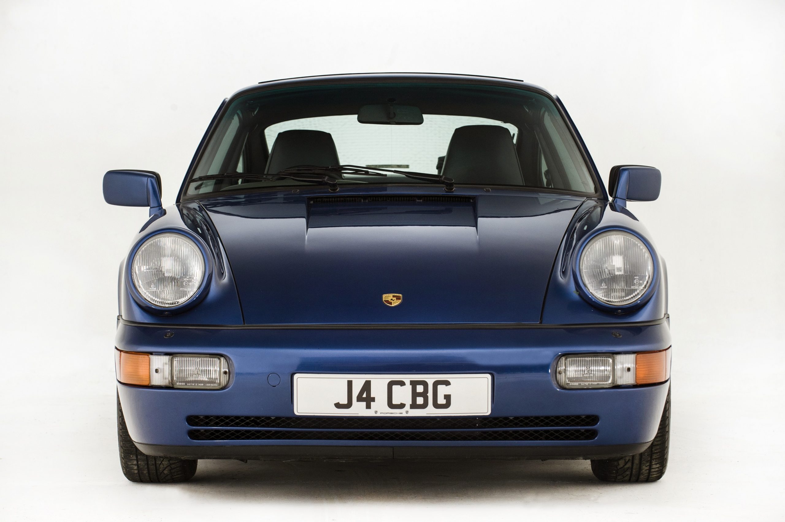 A blue 1991 Porsche 911 shot from the front in a photo studio