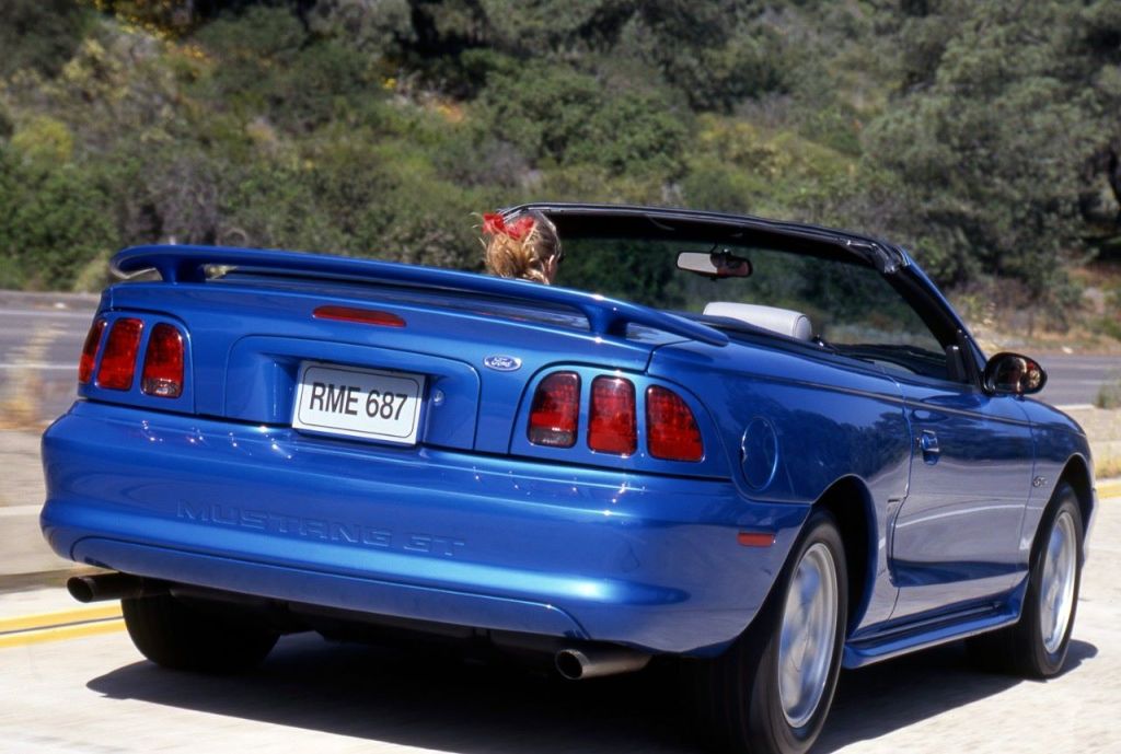 Blue 1998 Ford Mustang Convertble driving on a coastal highway